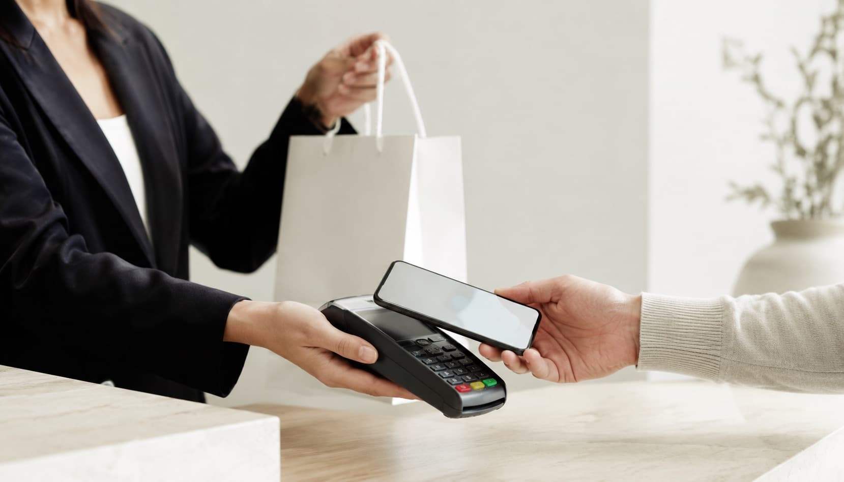 Payment processing in action — a customer paying by phone on a contactless POS terminal at a retail counter